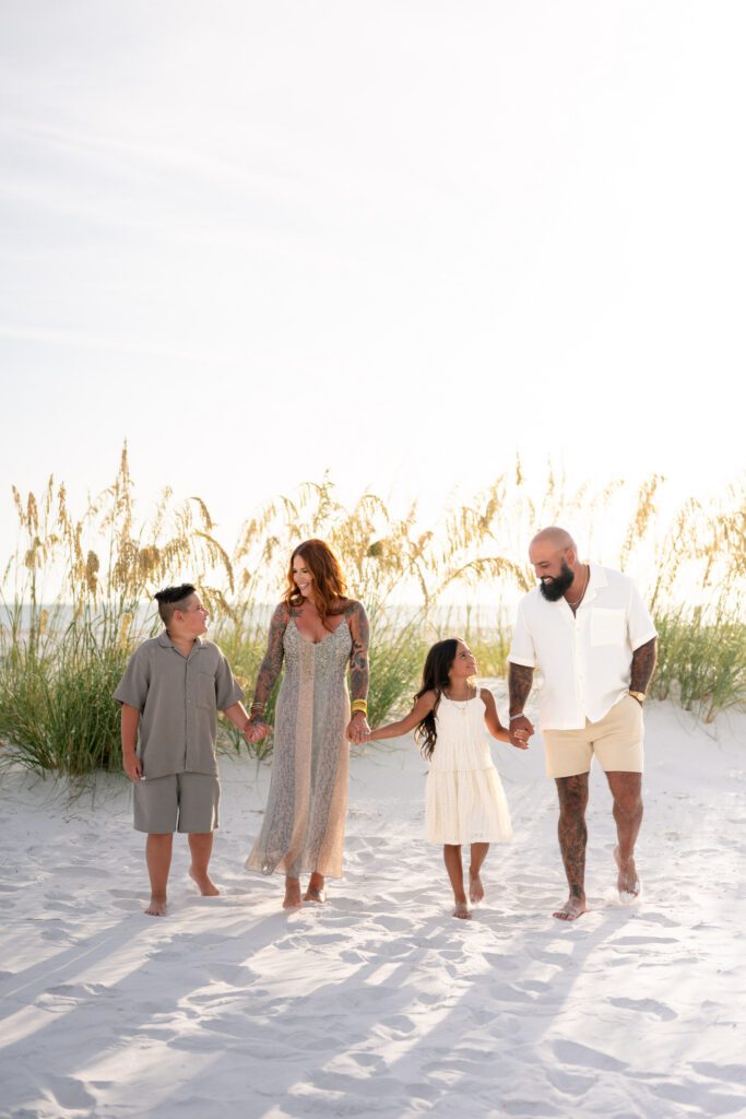 Family walking together through sand dunes during Bean Point Beach family photography session on Anna Maria Island