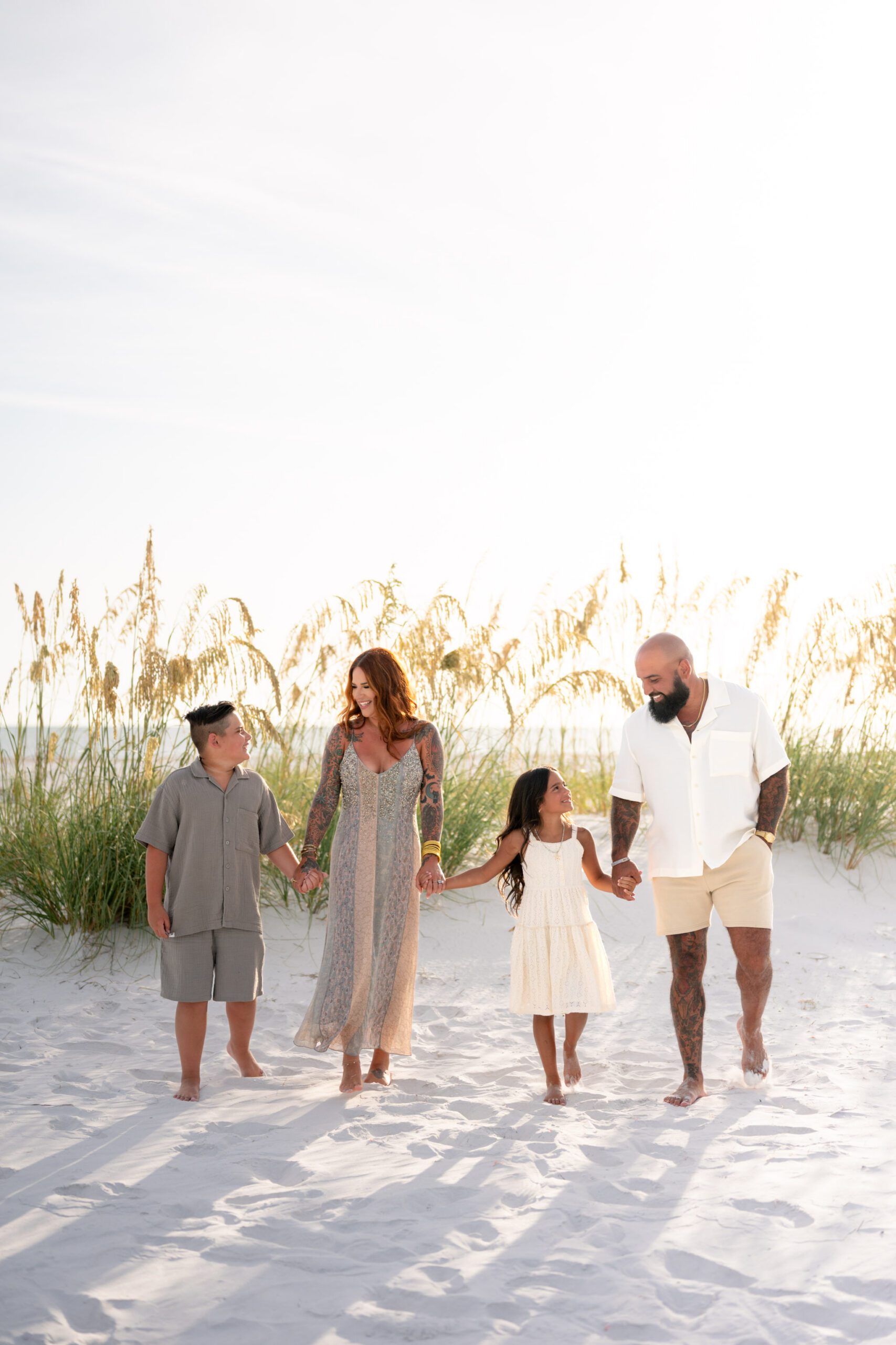 Family walking together through sand dunes during Bean Point Beach family photography session on Anna Maria Island