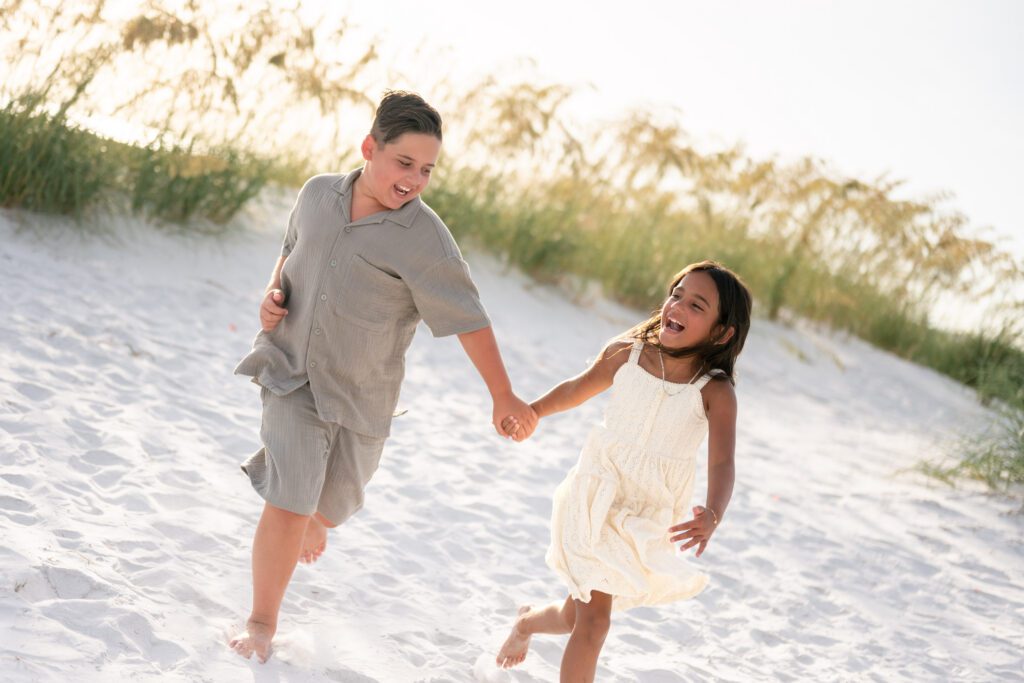 Children running together during Bean Point Beach family photography session on Anna Maria Island