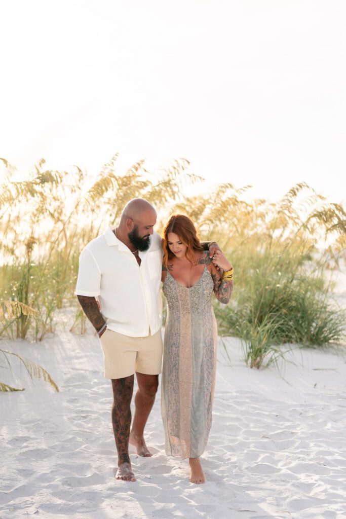 Parents walking together through sand dunes during Bean Point Beach family photos on Anna Maria Island