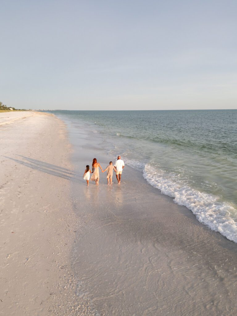 Family walking along shoreline at Bean Point Beach during Anna Maria Island family photography session