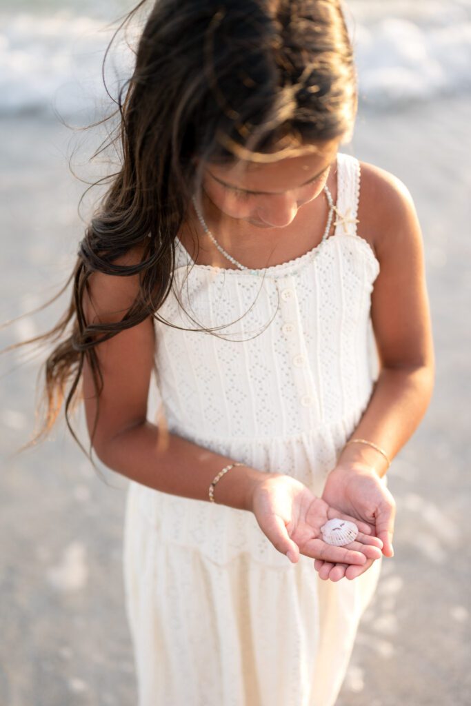 Child holding seashell during Bean Point Beach family photos on Anna Maria Island
