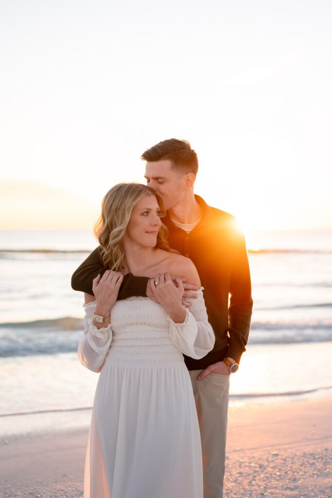 Romantic sunset portrait of a couple embracing during their Siesta Key Beach engagement session with warm coastal light in Sarasota, Florida