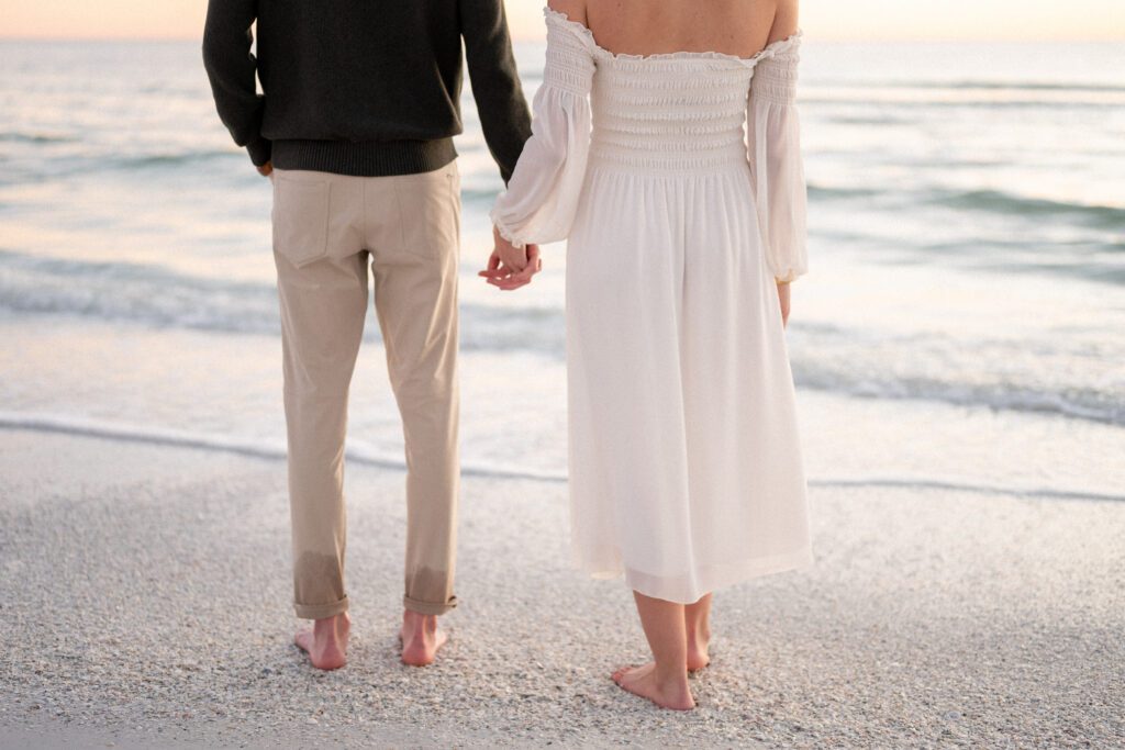 Close-up of a couple walking barefoot along the shoreline during a Siesta Key Beach engagement session on Florida’s Gulf Coast