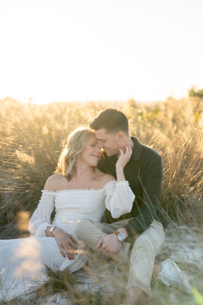 Romantic seated couple in the dunes during Siesta Key Beach engagement photos with soft golden hour light along Sarasota’s coast