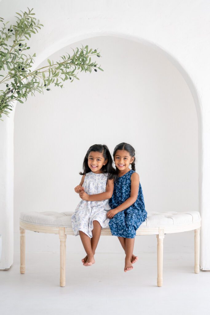 Sisters sitting together during Orlando studio family photography session in natural light studio