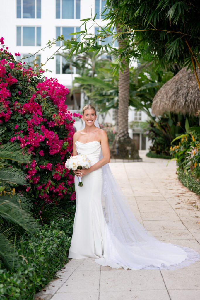 Bride standing along a tropical garden pathway with vibrant florals and a flowing veil, captured during a Miami destination wedding at The Palms Hotel & Spa Miami Beach