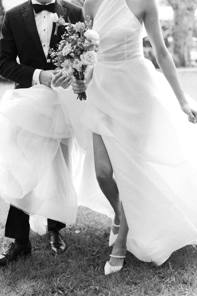 Black and white detail of the bride’s flowing wedding dress and bouquet captured in motion during an Up The Creek Farms wedding photographer session