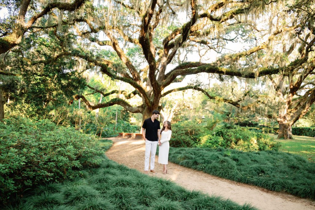 Couple walking beneath a sprawling oak tree during a Washington Oaks Gardens State Park engagement session in Palm Coast, Florida
