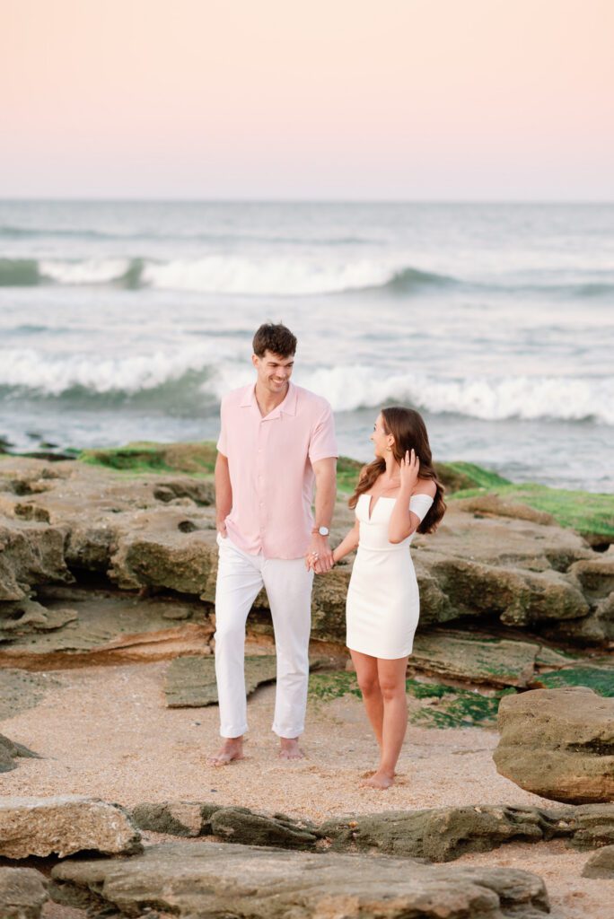 Couple walking along the coquina rock shoreline during a Washington Oaks Gardens State Park engagement session in Palm Coast, Florida