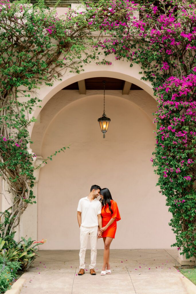 Couple standing beneath a bougainvillea-covered arch along Worth Avenue in Palm Beach after a Worth Avenue Clock Tower proposal